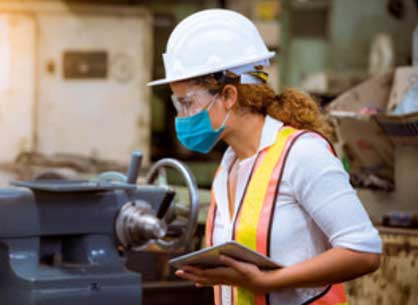 A female industrial plant worker inspecting with a tablet in hand.