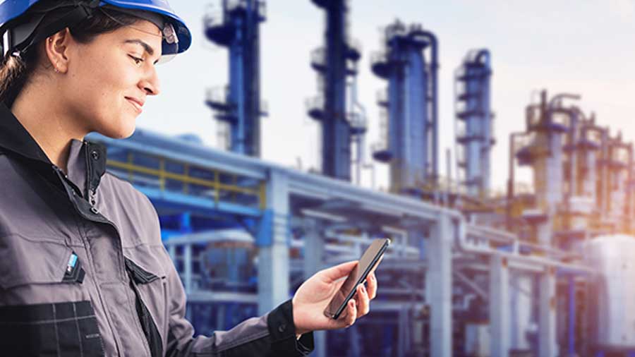 A woman at an industrial gas facility looking at her phone