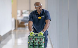 A hospital worker pusing a cart of Intelli-OX portable medical oxygen cylinders