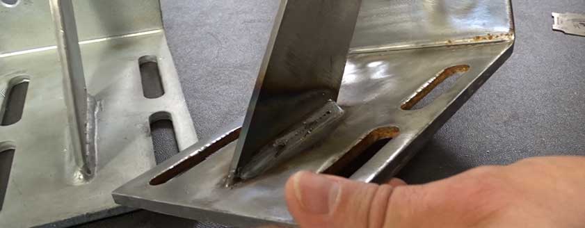 An Advanced Fabrication expert comparing the weld quality on two brackets.