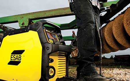Man uses ESAB welding machine to perform maintenance, repair and operations (MRO) application on a tractor plough in a farm field.