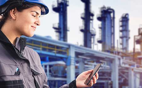 Set in a warehouse/distribution center, a smiling worker with a headset sits at a desk and works at a computer displaying the Airgas.com homepage.