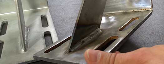 An Advanced Fabrication expert comparing the weld quality on two brackets.
