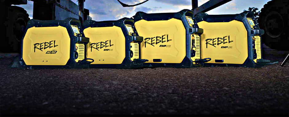 Four yellow and black Rebel EMP welding machines are lined up on the ground outdoors, ready for action with MIG and TIG welding capabilities, industrial equipment humming in the background.